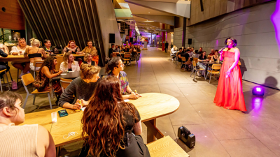 A drag bingo host and audience playing drag bingo.