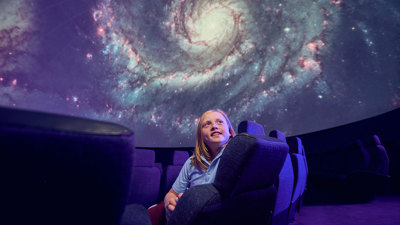 A secondary school student observes a projection of a spiral galaxy on the dome of the Melbourne Planetarium   