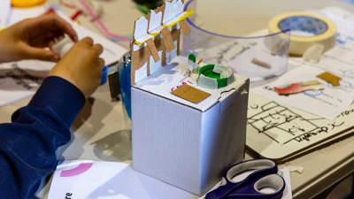 A student uses cardboard, tape and paints to craft during a design sprint at Scienceworks.