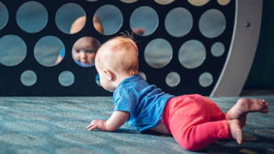 A baby looking at themselves in a group of circular mirrors