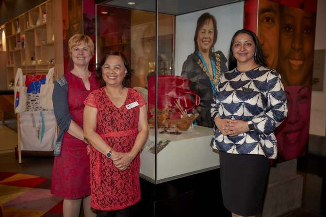 Three women in front of a red suitcase in a museum exhibition