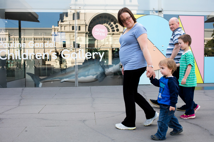 Two adults and two children walking in front of Melbourne Museum