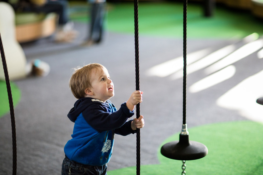 Toddler pulling on the ropes of the Kinetic Sculpture Wall in the Children's Gallery