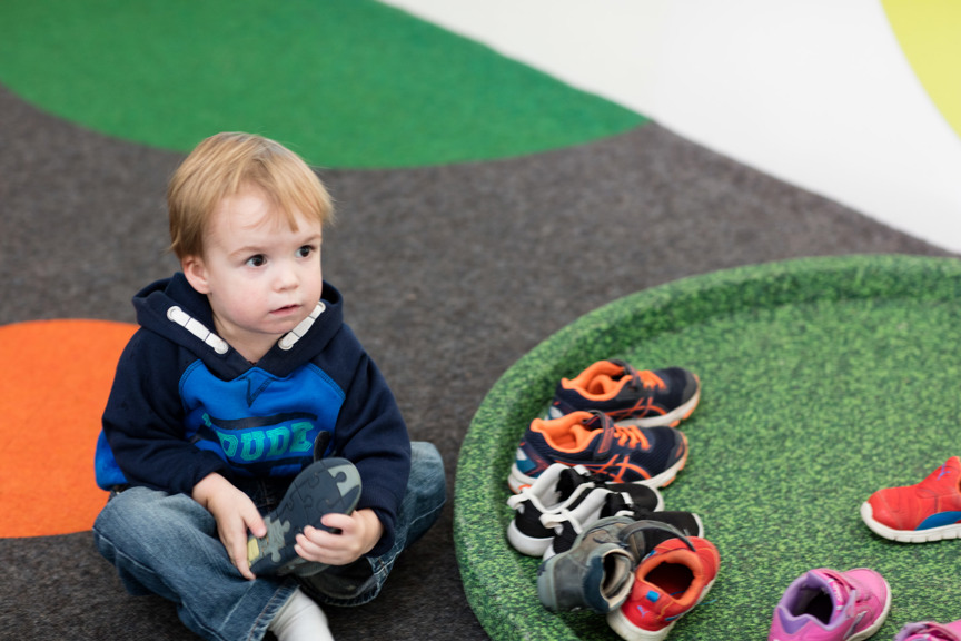 Toddler taking his shoes off in the Children's Gallery