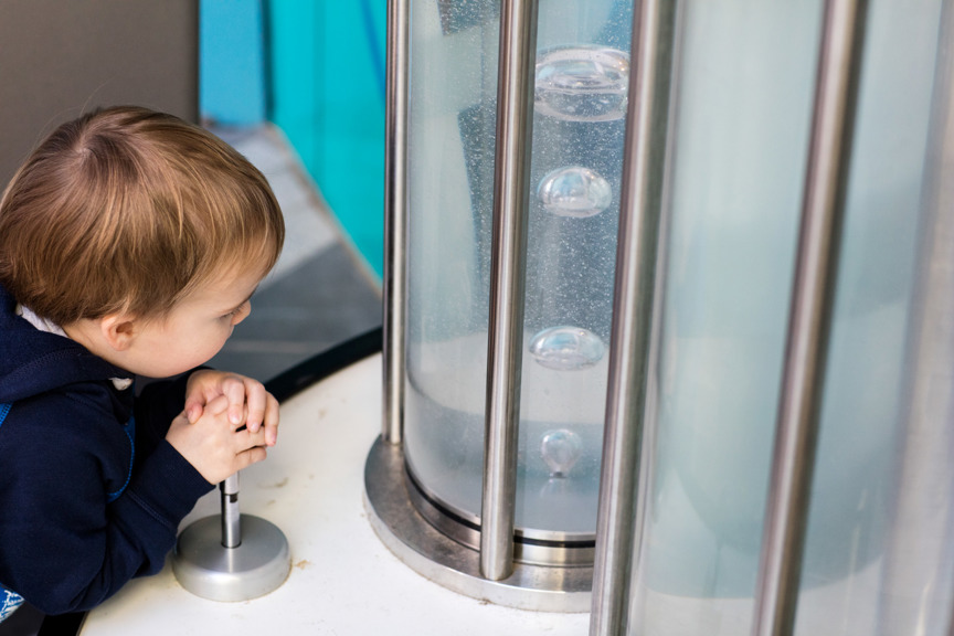 Toddler playing with the bubble maker in the Children's Gallery outdoor playground