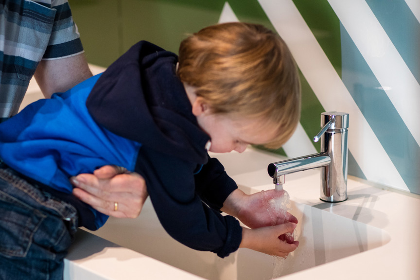 Toddler washing his hands at a sink in the family bathrooms at the Children's Gallery