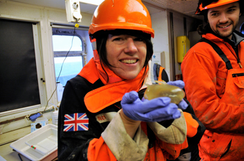 Melanie Mackenzie holding a marine invertebrate known as a Sea Pig during an Antarctic research voyage.