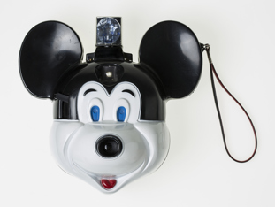 Black and white camera in shape of Mickey Mouse with flash at top of head and wrist strap.