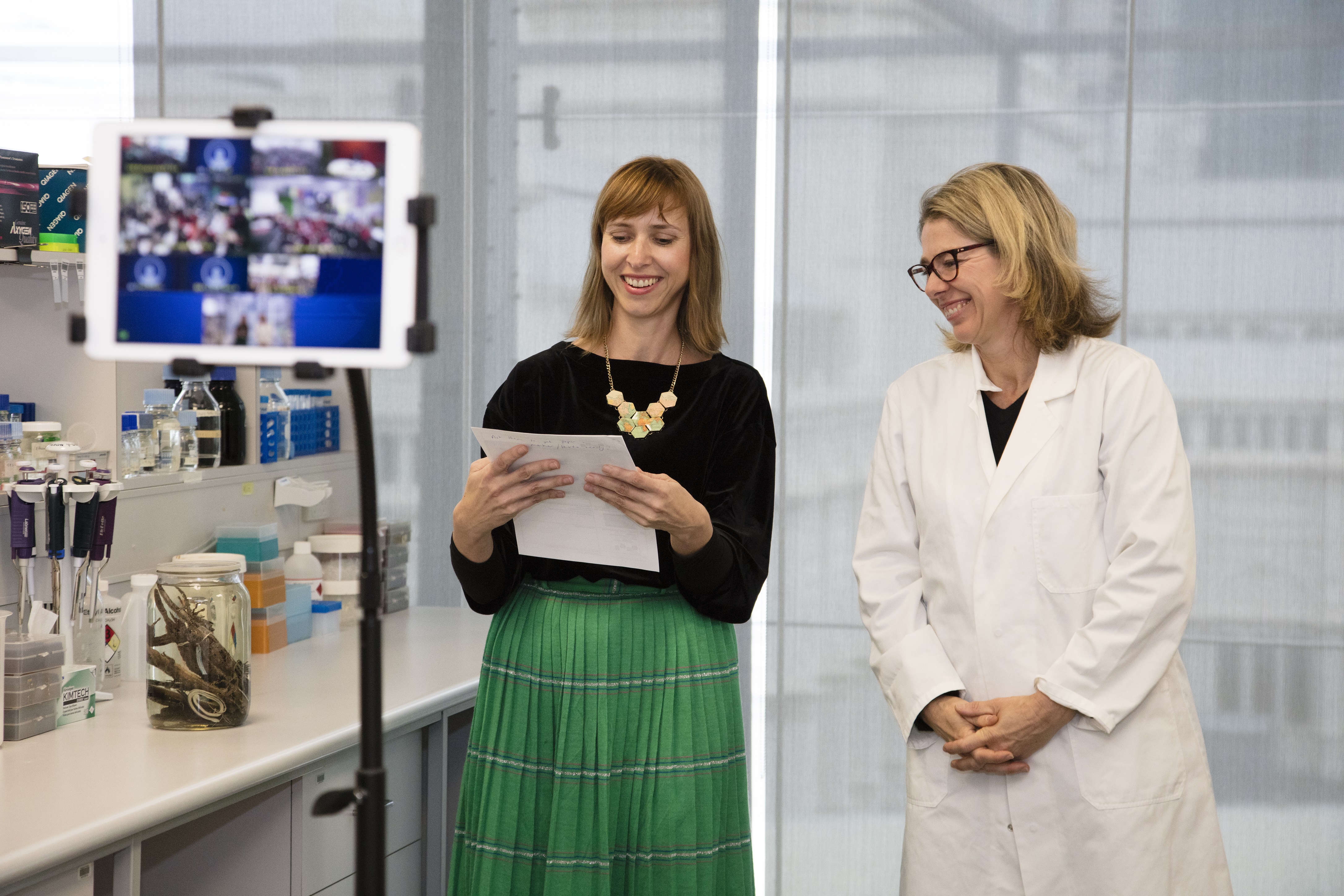 Two museum staff presenting to an iPad which shows schools watching from the classroom.