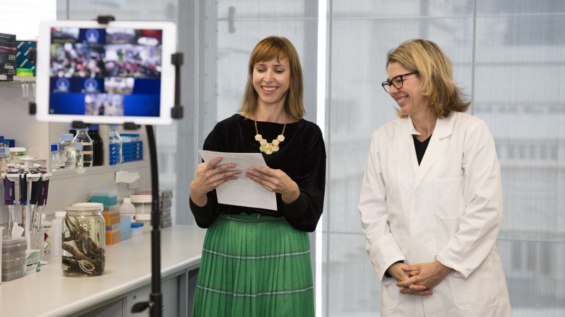 Two museum staff presenting to an iPad which shows schools watching from the classroom.