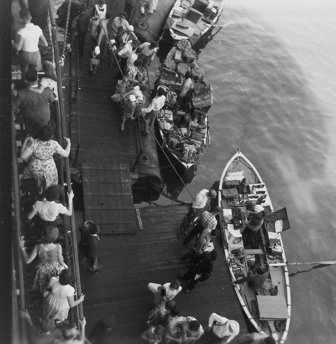 Passengers buying from boats alongside a liner at the Port Said floating market, circa 1959.