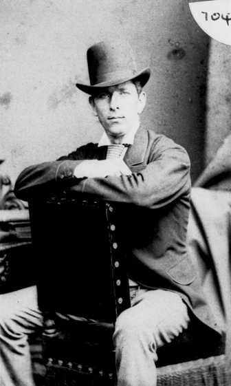 Man in hat and coat sitting backwards in chair