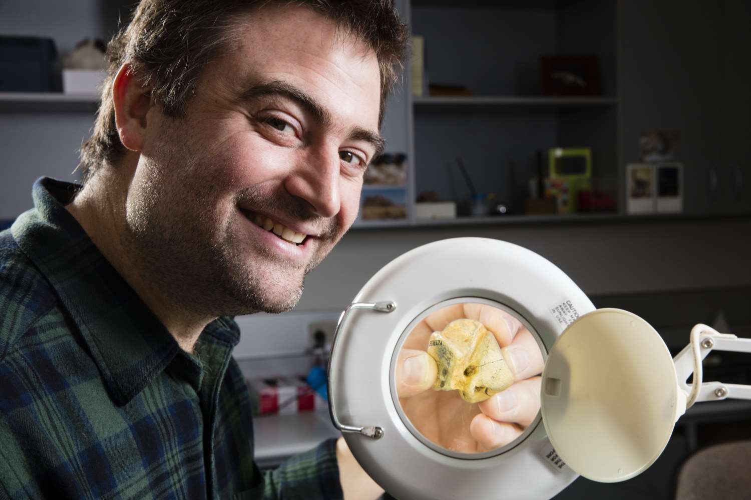man with fossil through magnifying glass