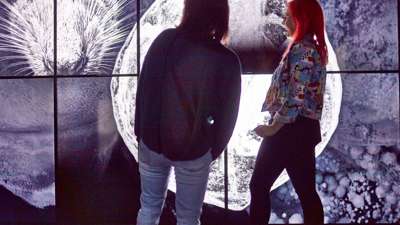 Two women in front of large video displays