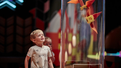 Young boy playing with suction tube exhibit in the Ground Up exhibition at Scienceworks