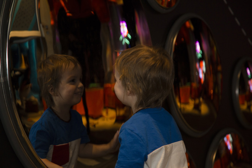 Boy playing with mirrors in Ground Up exhibition at Scienceworks.