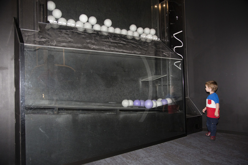 Boy looking at the ball dropping interactive in Ground Up exhibition at Scienceworks.