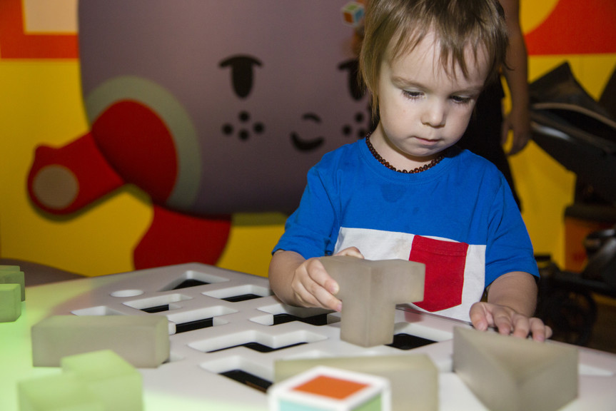 Boy playing with block shapes in Ground Up exhibition at Scienceworks. 