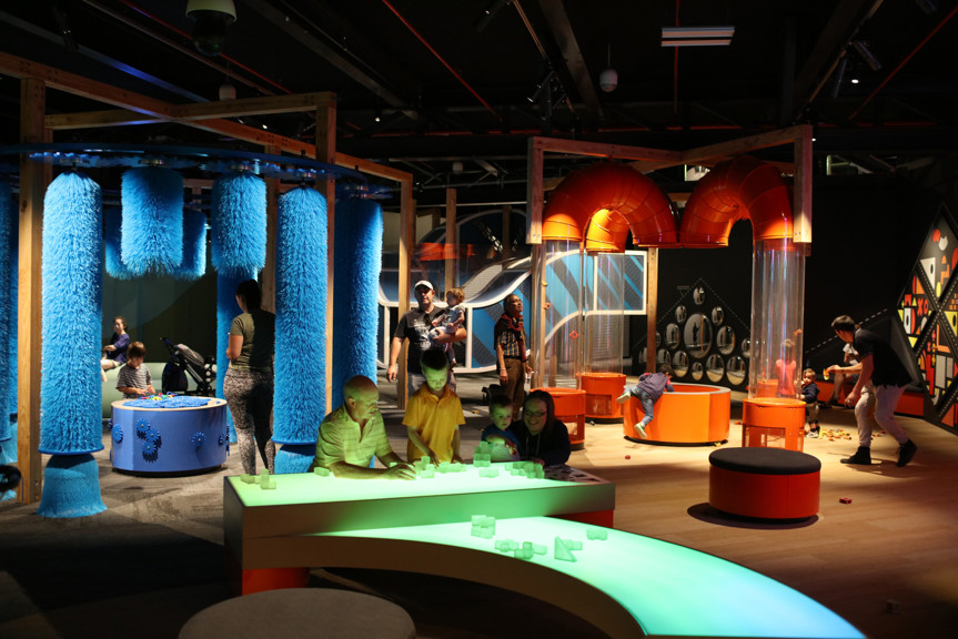 Family playing with building blocks on the light-up table in the Ground Up exhibition at Scienceworks. 