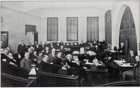 A room full of Victorian gentlemen in a municipal chamber