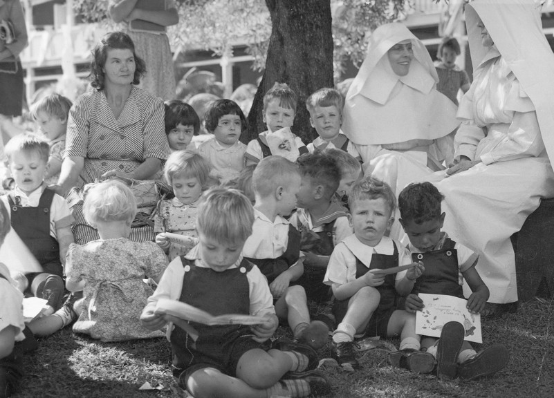 Group of children with 3 woman. Two are dressed a Nun's 