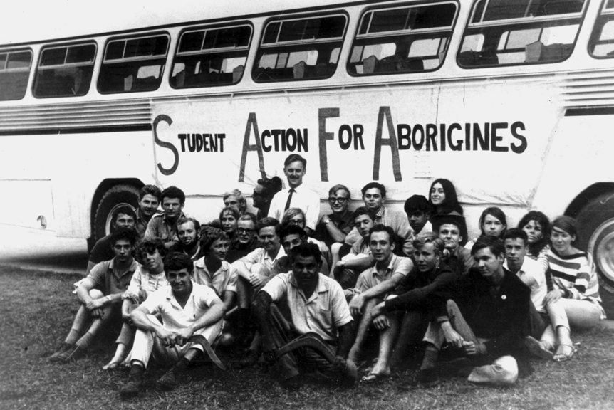 Group of people sitting beside a bus