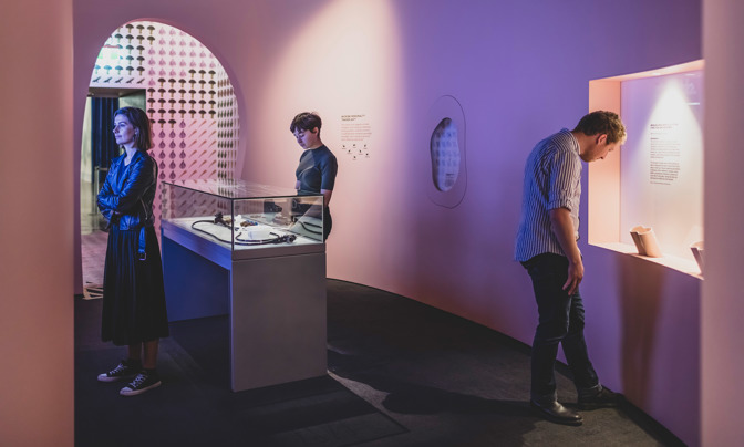 Three people looking an exhibition