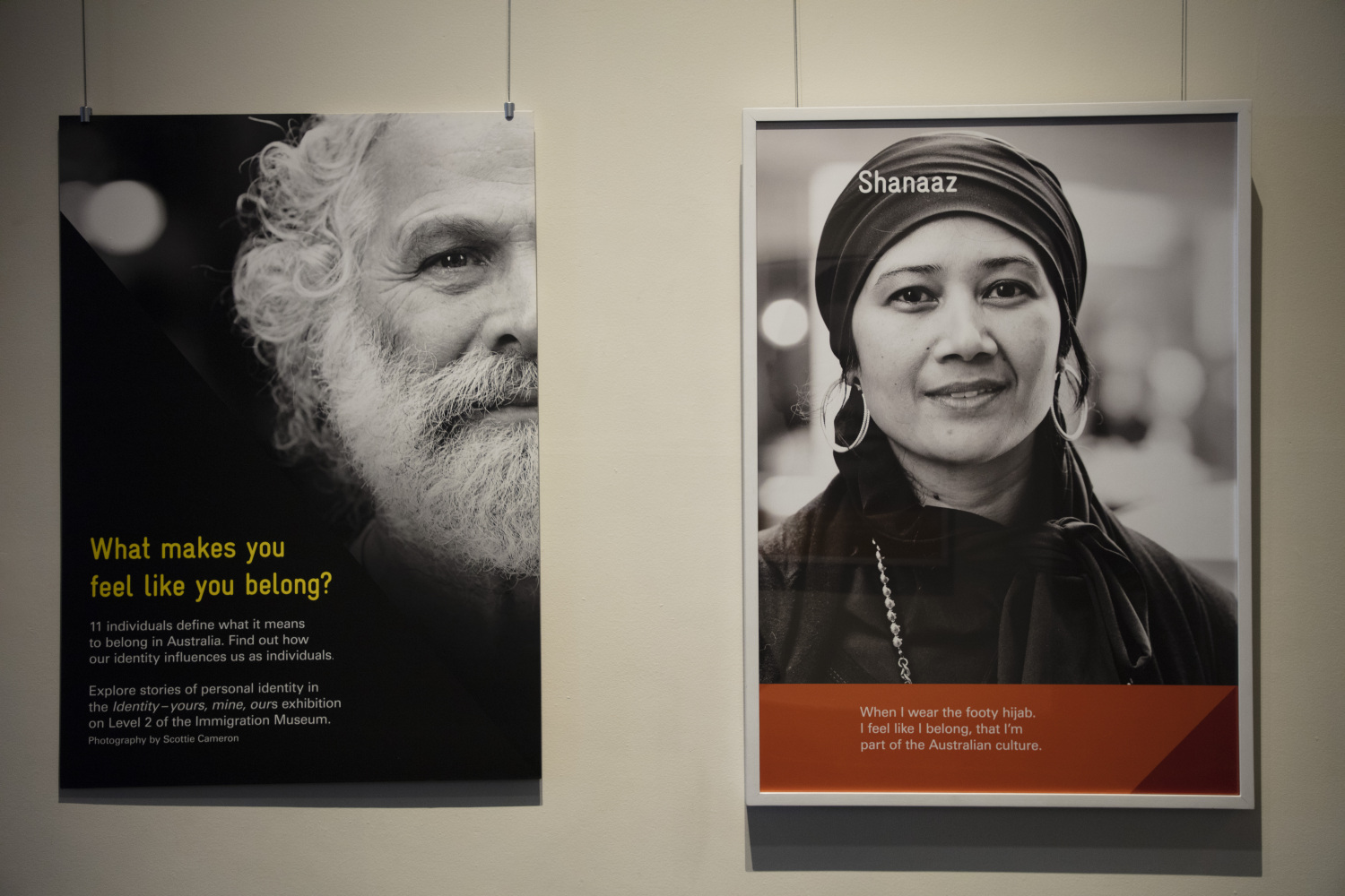The faces of a bearded man and a woman wearing a head covering, hanging on boards suspended from the ceiling as part of the Identity: yours, mine, ours exhibition.