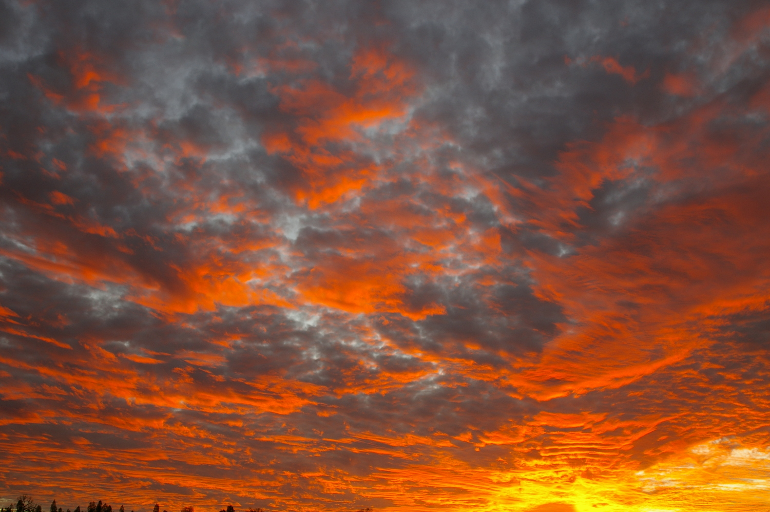 A bright orange and yellow sunset interspersed with grey clouds.