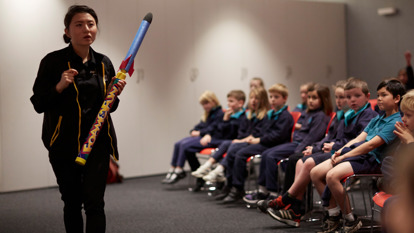 A Scienceworks presenter talks to a group of primary school students while holding a toy rocket in the Blast Off show.