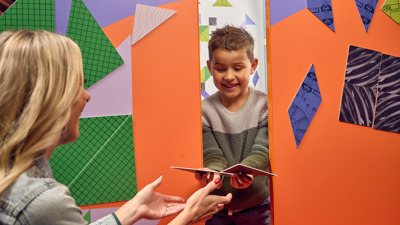 A parent and child solving a Tangram puzzle together.