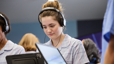 A student wearing headphones interacts with an iPad as part of Road Smart Interactive 
