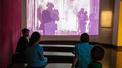  Primary school students viewing the audiovisual display in the Leaving Home exhibition in Immigration Museum.