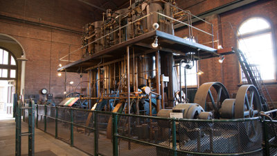 Large steam engine in a red brick building.