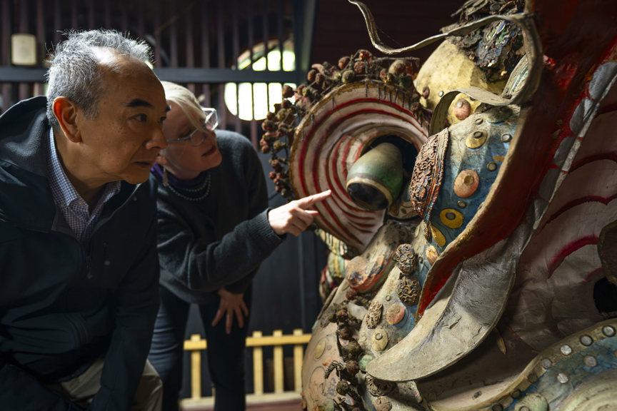 a man and a woman looking over a colourful Chinese dragon head