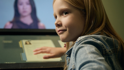 A girl uses an interactive display in Leaving Home exhibition at the Immigration Museum.