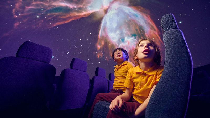 Two primary school students observing astronomy projections on the dome of the Melbourne Planetarium
