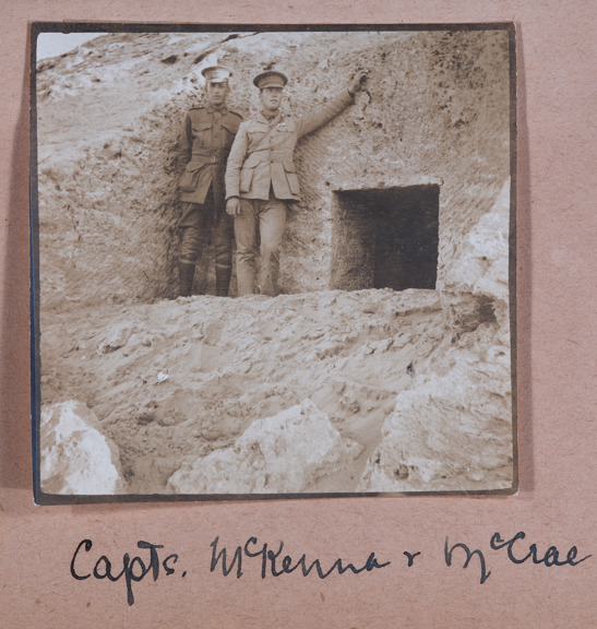 two men in military uniform standing next to a square cut opening in rock 