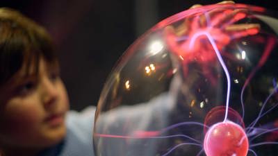 Child with a lightning-touch plasma ball at the 'Glow Show' in the Lightning Theatre at Scienceworks during a Glow Show.