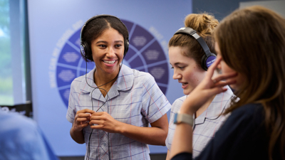 A learning facilitator talks to two students wearing headphones as part of Road Smart Interactive 
