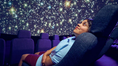 A secondary school student observes a projection of the cosmos on the dome of the Melbourne Planetarium