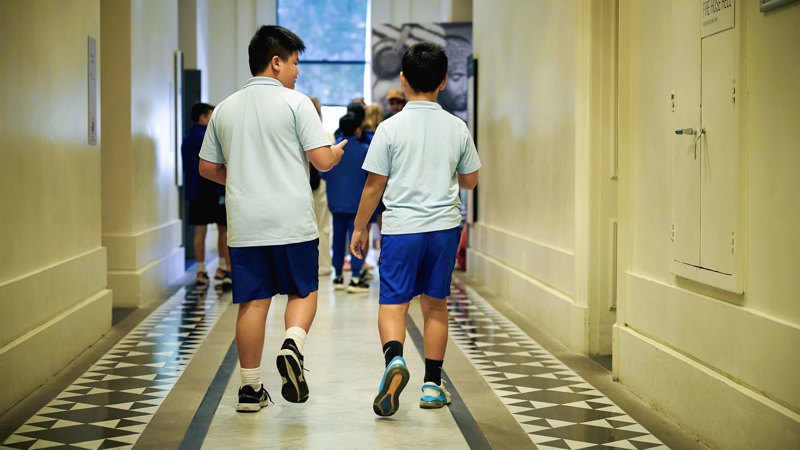 Two students walking through a corridor at the Immigration Museum on a school excursion.  