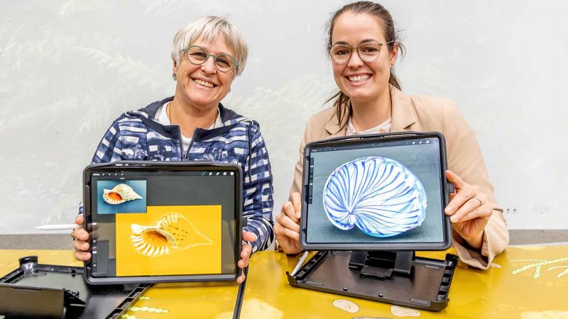 Two people show off their digital artworks on iPads in the Learning Lab at Melbourne Museum during a Digital Art Class.