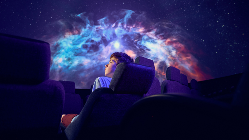A secondary school student observes a projection on the dome of the Melbourne Planetarium during a school excursion 