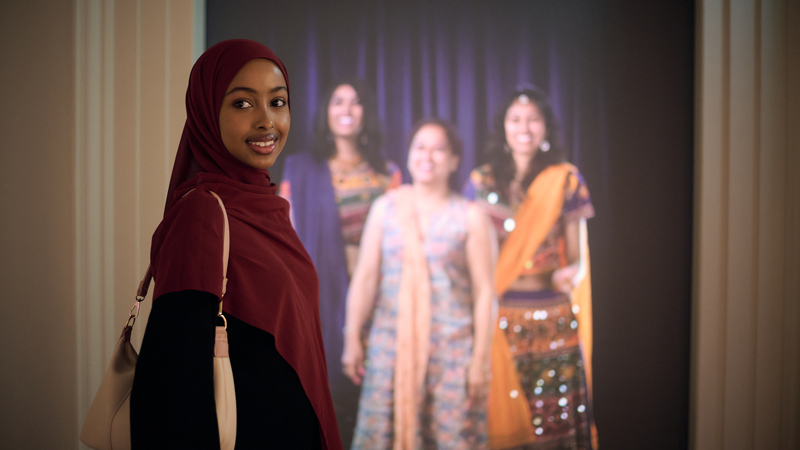 A woman in a hijab stands a display in Identity: Yours, Mine, Ours exhibition at the Immigration Museum.
