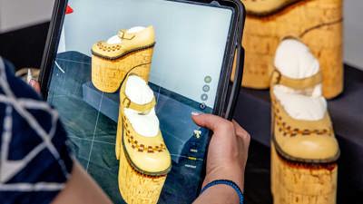 A person uses an iPad to photograph shoes in the Learning Lab at Melbourne Museum during a Digital Art Class.