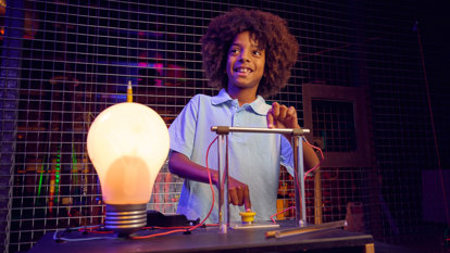 A child does a science experiment with a huge lightbulb in the Lightning Theatre at Scienceworks.