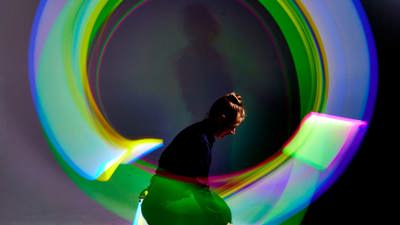  Person waving a light source in each hand to create a circle-shaped light pattern in a variety of colours during the Glow Show at Scienceworks.
