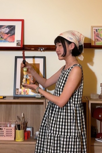 Amy Yang in a checkered dress holding a crafted candle stick holder.
