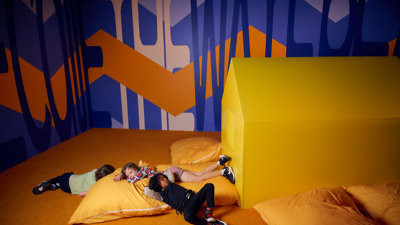 Children recline on large yellow pillows.